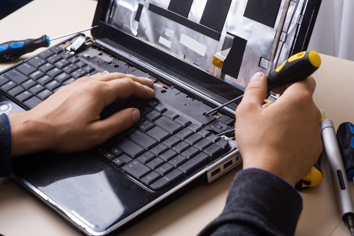 technician carefully opening the laptop panel above keyboard using a screw driver
