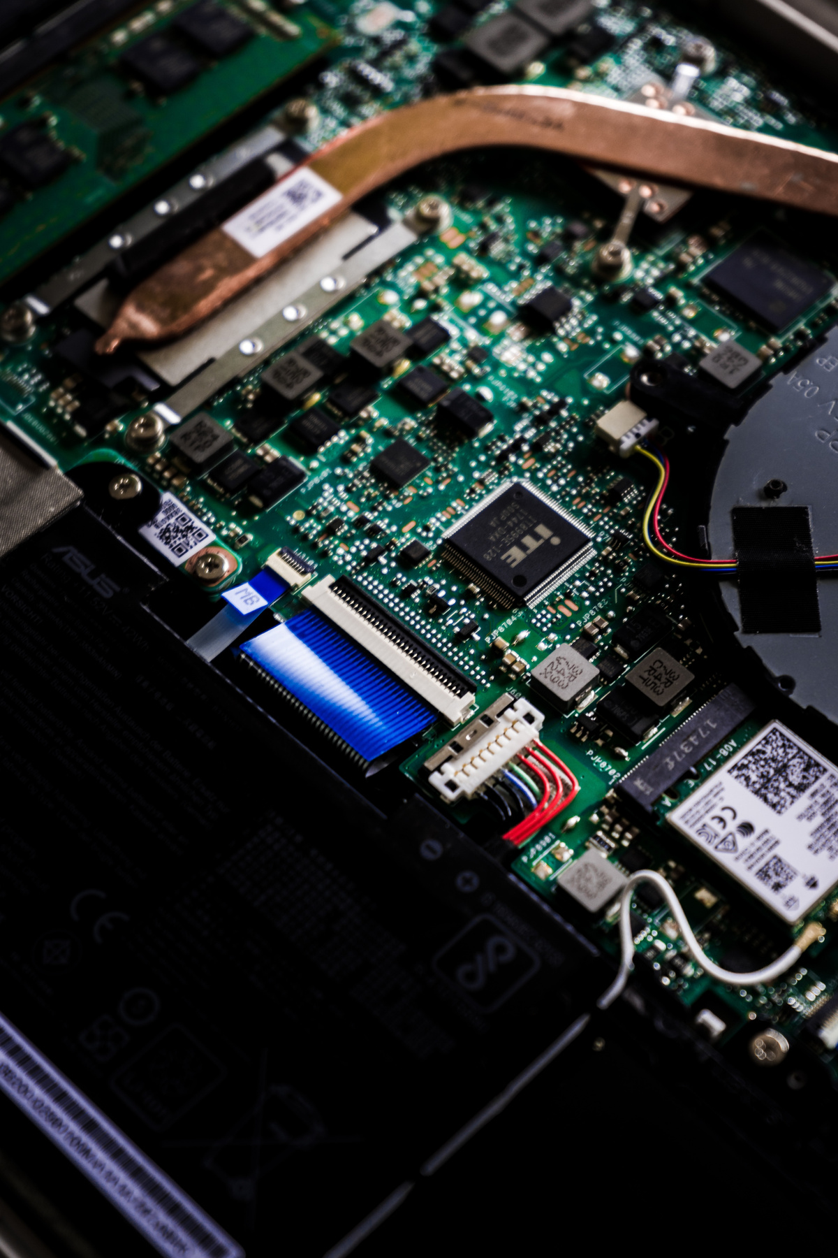 laptop motherboard showing embedded controller, wifi card, fan, keyboard flex cable, backlight connector, battery connector, coils and components